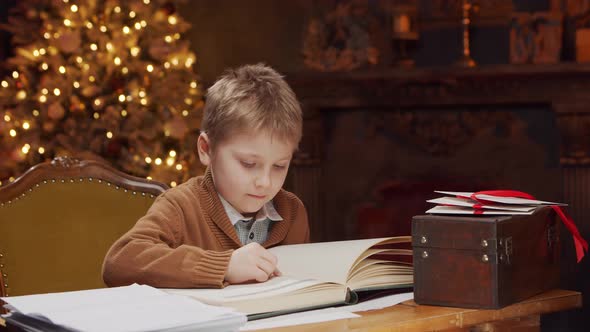Little boy reads a magic book while sitting at the table. Christmas concept.
