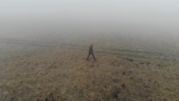 A Caucasian Man in Tourist Clothing Walks on the Top of a Plateau Next to a Deep Cliff Along with a