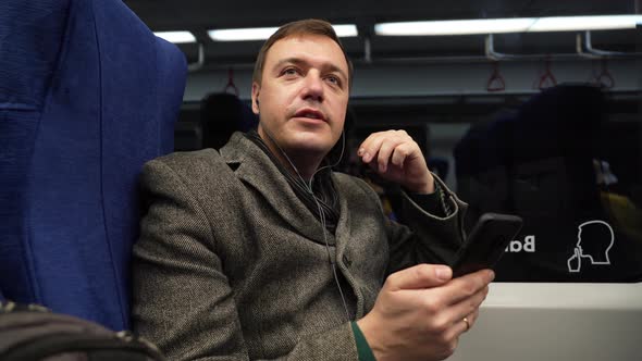 Mature Guy in Gray Coat Riding on Train Using Mobile Phone Discusses Work Processes on Videocall