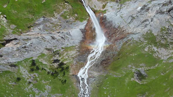 Aerial: drone flying over scenic high waterfall lush green valley and mountain stream on the Alps