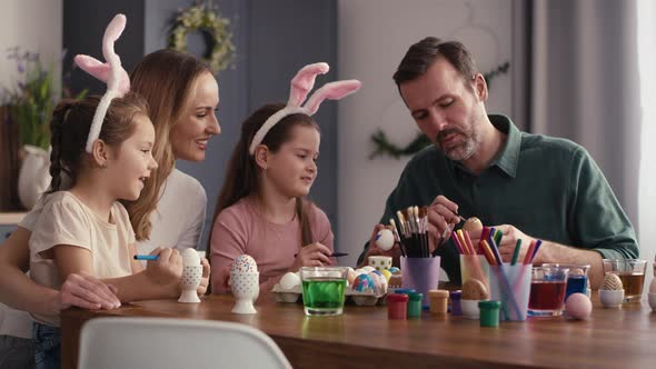 Static video of caucasian family of four people decorating easter eggs at home. Shot with RED helium