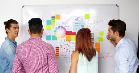 Business executives writing on white board with marker