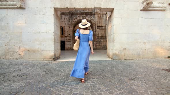 Young woman in a blue dress walking on the street in the city. Split, Croatia