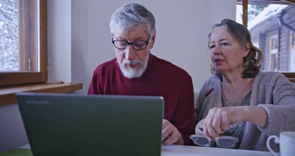 an Elderly Man and His Wife are Dealing with Information on a Laptop