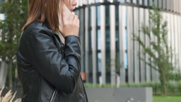 Smiling Business Woman Talking to the Smartphone with a Client Near Business Centre