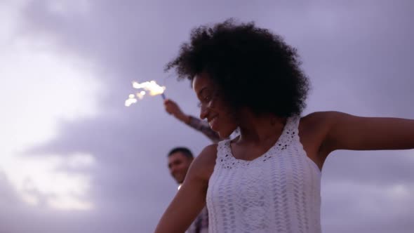 Couple dancing with sparklers on beach at dusk 4k