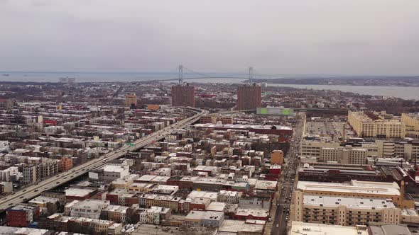 an aerial drone shot, panning left over Sunset Park Brooklyn. It's a cloudy day & the Verrazano Brid