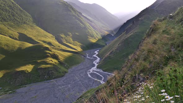 Sunset in the Caucasus Mountains in Tusheti, Georgia. A Narrow Stream Is Seen Below. A Much Bigger