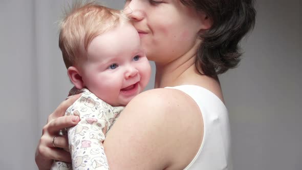 Cute Little Baby is Smiling While the Mother is Hugging Him with Her Arms