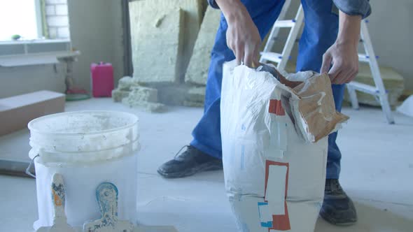 A Worker Kneads the Mixture Into Plaster Buckets