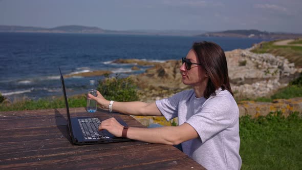 A Girl in Nature Works at a Computer