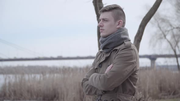 Sad Caucasian Man Standing on Riverbank and Thinking. Portrait of Young Depressed Lonely Guy