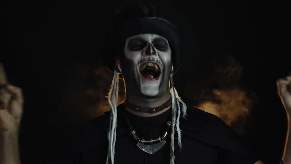 Frightening Man in Skeleton Halloween Cosplay Makeup Wearing Earphones, Dancing, Celebrating