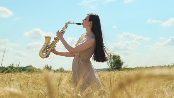 Beautiful Longhaired Brunette Woman Jazz Performer Plays Saxophone Outdoors in Field with Blue Sky