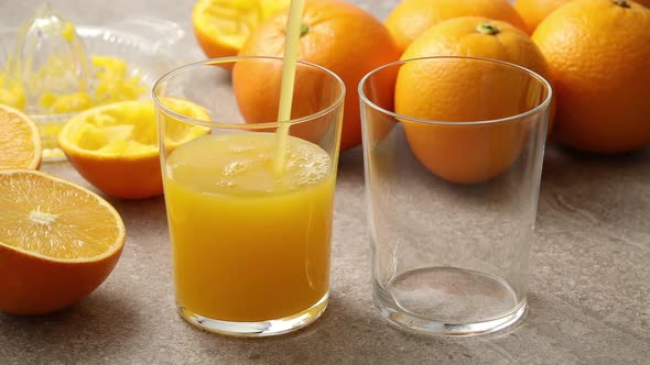 Pouring fresh pressed orange juice in glasses 