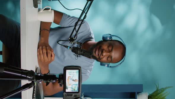 Vertical Video Cheerful Vlogger Waving at Camera While Recording Podcast