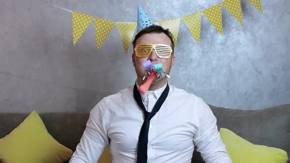 Young Man In A Festive Hat Celebrates A Birthday. Cheerful Happy Young Man Celebrates The Holiday