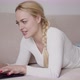 Blond Female Lying on Sofa and Browsing Laptop - VideoHive Item for Sale