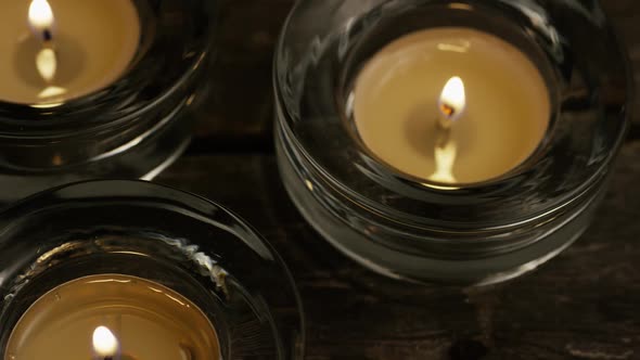 Tea candles with flaming wicks on a wooden background - CANDLES 024