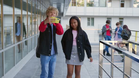 African and Caucasian Schoolkids Make Video on Smartphone Outside School