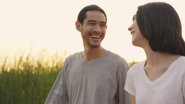 Asian young couple walking outdoor in the evening sunset in the field with happy and smile.