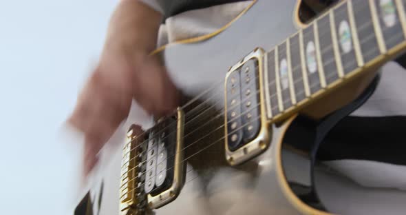 Dynamic Video of a Musician Quickly Plucking the Strings of a Guitar During a Performance on the