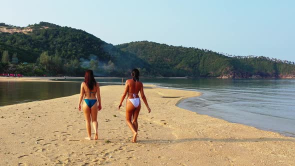 Beautiful ladies sunbathing on paradise island beach adventure by shallow ocean with white sand back