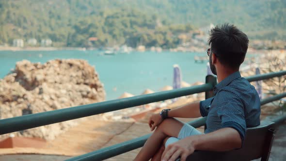 Lonely Romantic Guy In Sunglasses Sitting On Bench And Dreaming. Man Relaxing On City Beach.