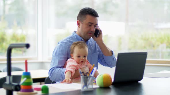 Father with Baby Calling on Phone at Home Office