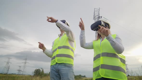 Two Engineers of Power Engineers in VR Glasses Move Their Hands Simulating the Operation of the