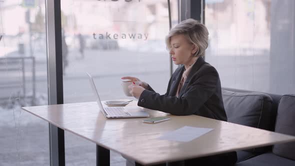 The Woman Works with a Laptop in a Cafe