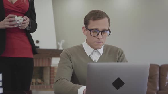 Portrait Young Busy Serious Modestly Dressed Man in Glasses Sitting at the Table at Home with Beautiful Woman