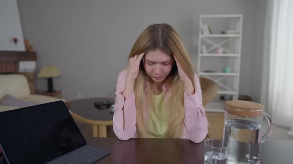 Portrait of Overburdened Overwhelmed Young Woman Rubbing Temples Holding Head in Hands Sitting at