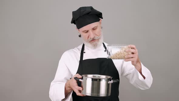 Middle Aged Chef Man Pouring Cereals on Grey Background