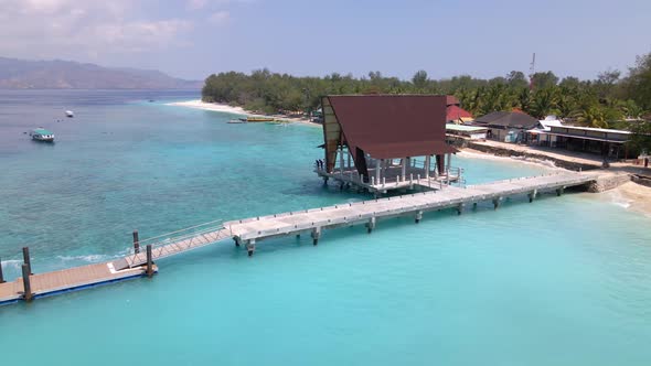 Aerial flyover tropical clear water with coral reefs and anchored boats and boathouse in paradise ba