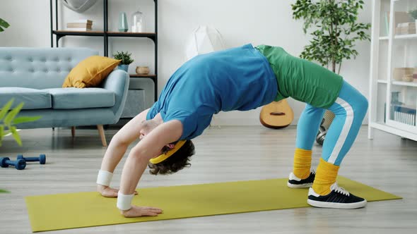 Sportsman in Retro Outfit Exercising in Crab Position on Yoga Mat Training Alone Concentrated on