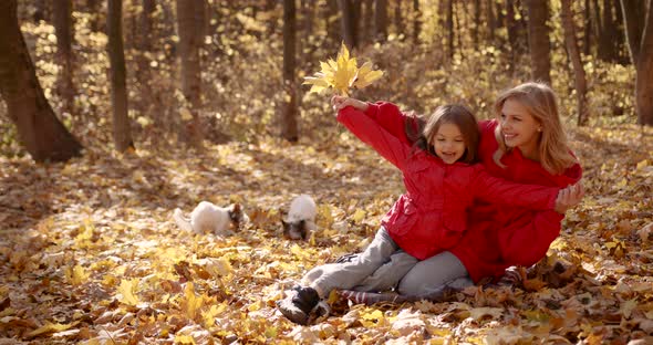 Mother with Daughter Sitting on a Blanket in the Autumn Forest