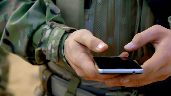 Mid section of caucasian military soldier using mobile phone during military training 4k