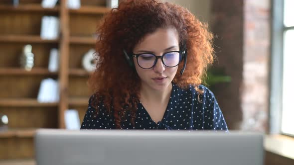 Curly Young Businesswoman in a Headset Holding Phone Call