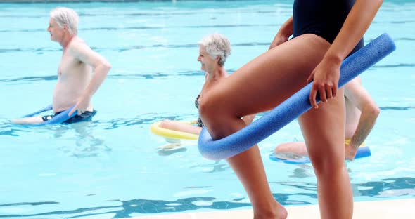 Swim trainer assisting seniors in performing exercise