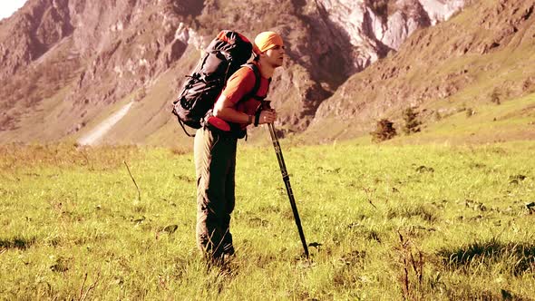 Hiking Man Walking on Green Mountain Meadow with Backpack. Summer Sport and Recreation Concept.