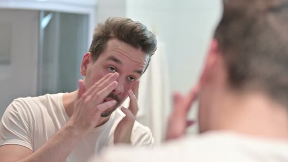 Young Man Putting Cream on Face in Mirror