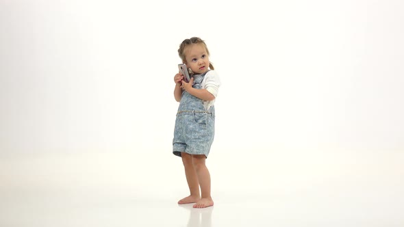 Baby Holds a Phone in His Hands and Talks. White Background