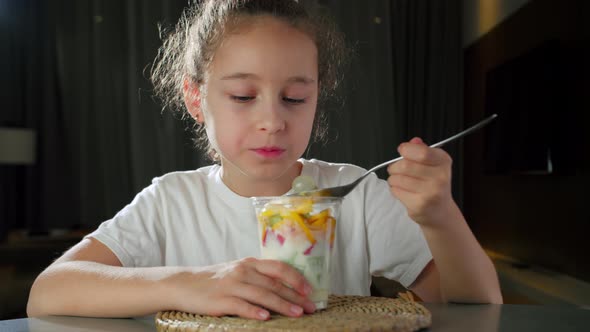 Child Eats Milk Yogurt with Tropical Fruits