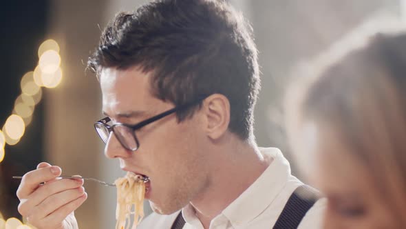 Close Up Portrait of Young Hipster Guy Eating at Table at Party or Celebration