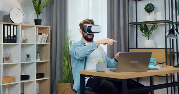 Guy in Augmented Reality Goggles Working on Imaginary Screen in Beautifully Decorated Home Office