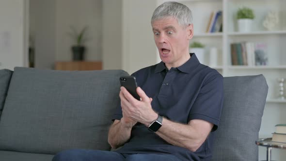 Middle Aged Businessman Having Loss on Smartphone on Sofa 