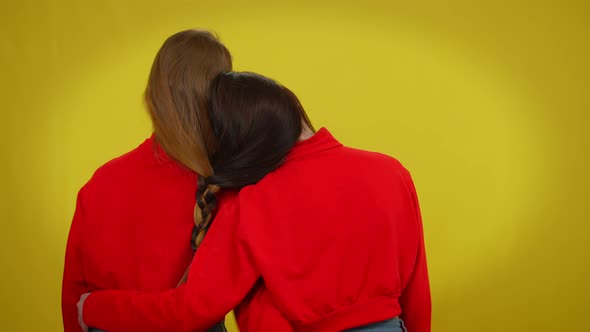 Back View Twin Sisters with Red and Black Hair Braided Together Standing at Yellow Background