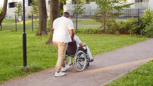 African-American caregiver and old disabled man in a wheelchair. Nurse and patient.