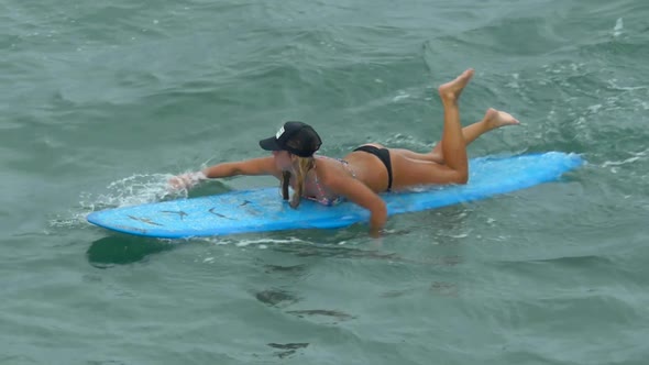 A young woman surfing in a bikini on a longboard surfboard.